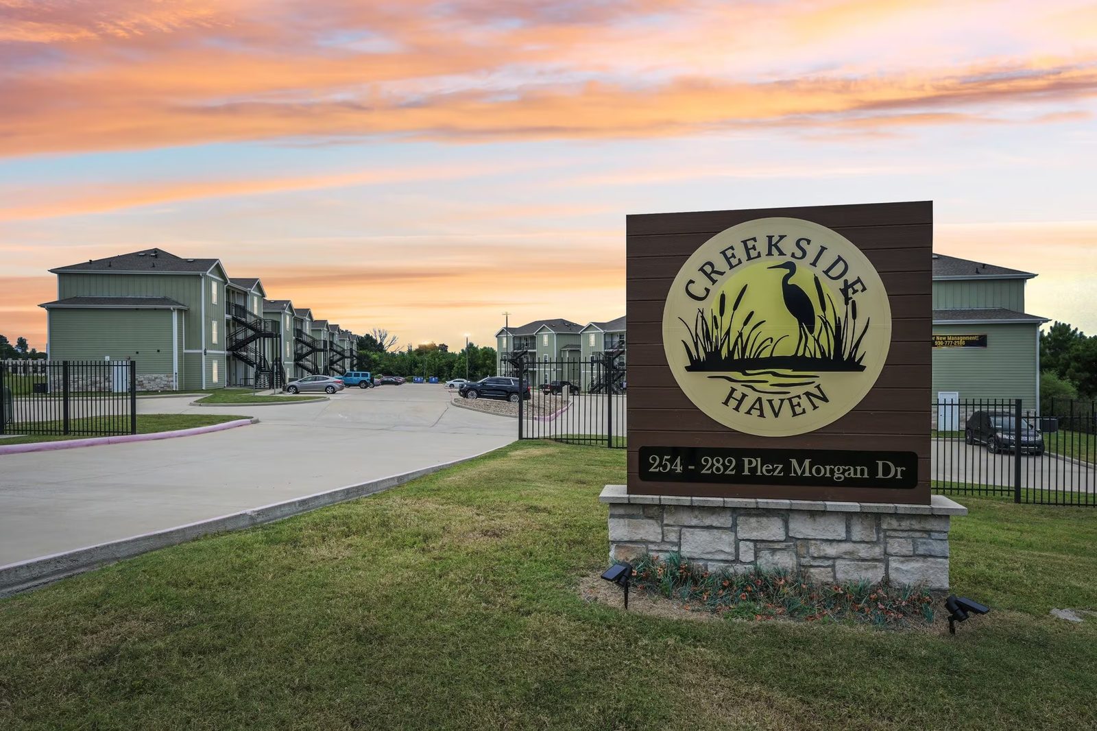The Creekside Haven entrance sign on Plez Morgan Drive at sunset, with the community's buildings behind it